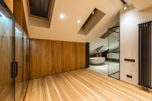 Creative design of bathroom with bath on floor under windows illuminated by lamps in house